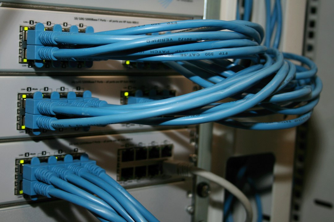 Close de cabos de rede azuis conectados a switches empilhados em um rack.